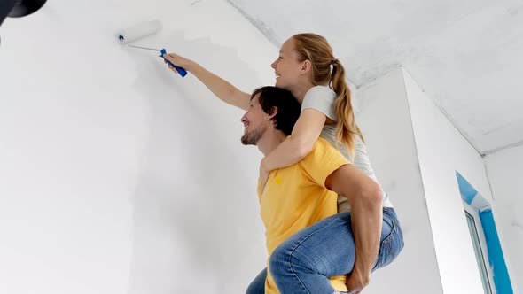 A Happy Man and Woman Paint the Wall Using a Roller Painter