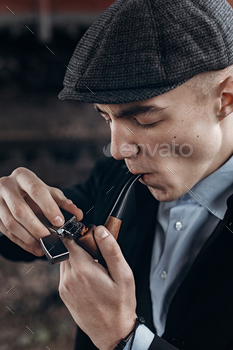 , lighting wooden pipe. england in 1920s theme. fashionable confident gangster. atmospheric moments. space for text