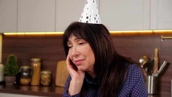 Close Up Upset Aged Woman in Party Hat Celebration Holiday Birthday Alone Home