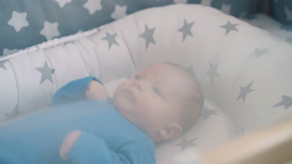 Funny Little Kid in Azure Clothes Lies in Cocoon with Stars