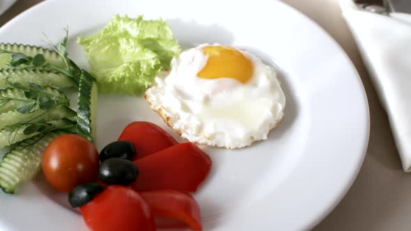 Fried Egg and Sliced Fresh Vegetables on Plate in Restaurant