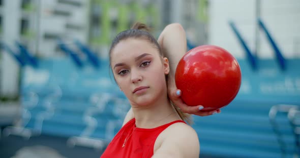 Portrait of Woman in Red Sports Costume Performing Callisthenics Exercises with Gymnastic Ball