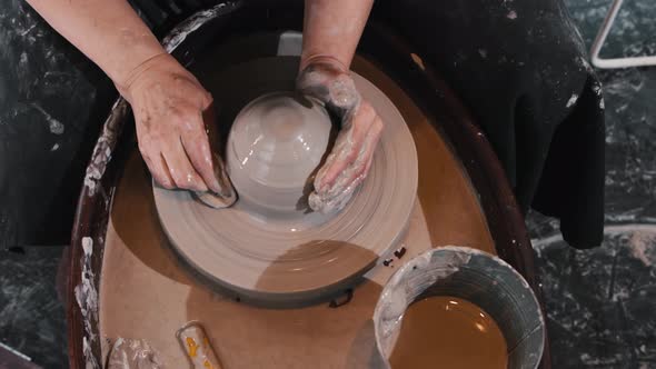 Pottery  an Elderly Woman Wetting the Clay on the Pottery Wheel