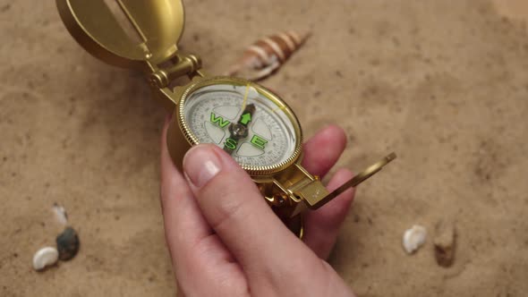 Man Hand Holding Gold Compass on Sand Background Closeup Golden Compass in Human Palm