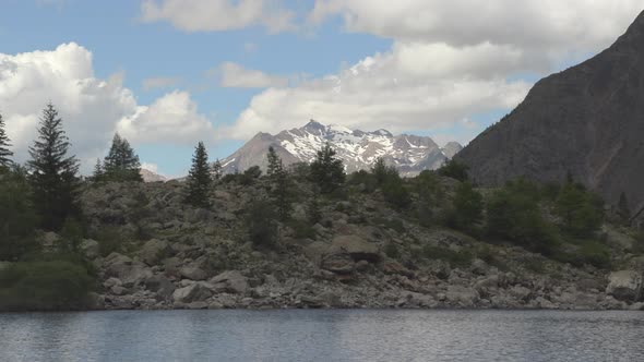 Timelapse in the french Alps showcasing a lake and a glacier mountain at the background. The clouds