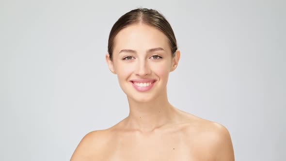 Beautiful Young Woman with Clean Fresh Skin Standing Over Light Grey Background