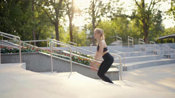 Young Fit Woman Doing Jump Squats on Stairs in Park Summer Day