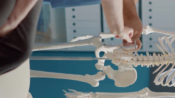 Vertical Video Male Doctor Pointing at Human Skeleton to Show Spinal Cord