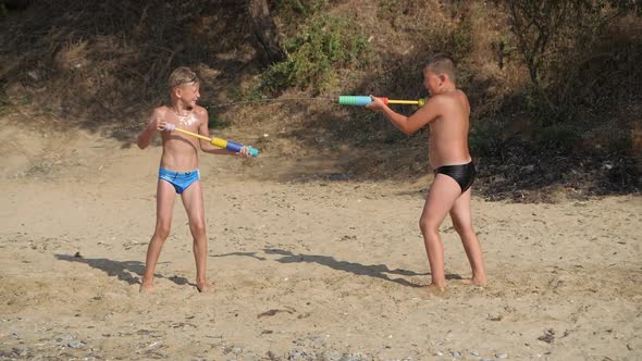 Boys Play with Water Pistols on the Sea Beach