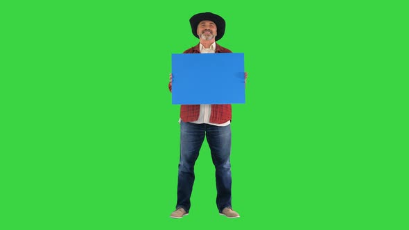 Farmer in a Cowboy Hat Standing with Blank Board and Smiling To Camera on a Green Screen Chroma Key