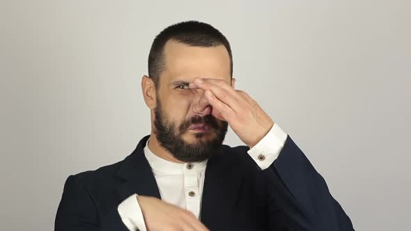 A Young Handsome Businessman Closes His Nose with His Fingers Feeling a Bad Smell.