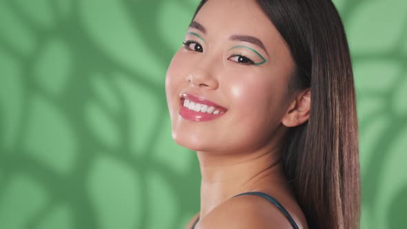 Young Happy Gorgeous Woman with Creative Eye Arrows Smiling to Camera Posing Over Green Background