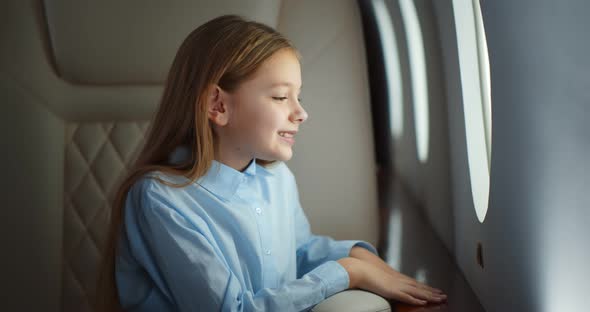 Child Sitting in Airplane Seat and Looking at Window