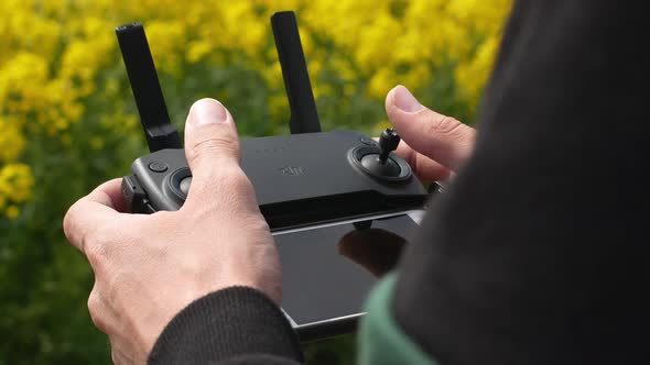 The man holds the remote control of the drone in his hands.