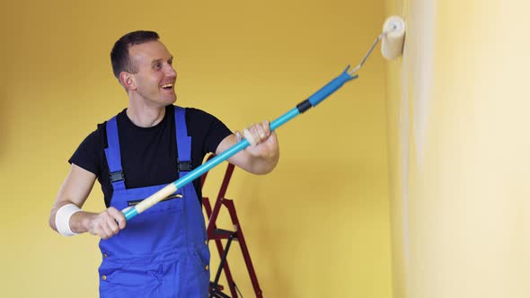 Young man painting wall with roller brush while renovating his apartment. 