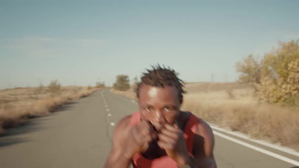 AfricanAmerican Man Stands on the Road in Sports Clothes and Trains His Hands