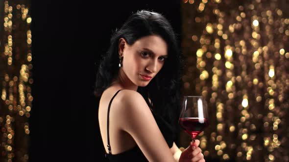 Seductive Asian Lady Posing Red Wine Goblet at Golden Illuminated Bokeh