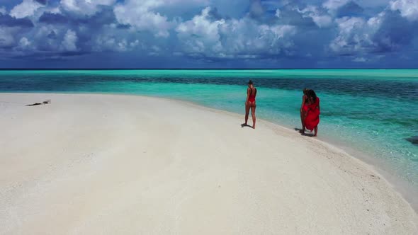Ladies together happy and smiling on exotic island beach vacation by shallow sea and white sandy bac