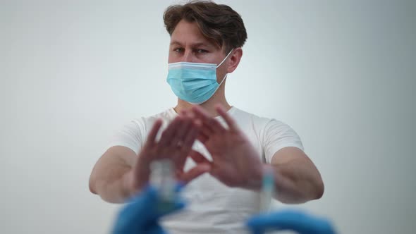 Portrait of Serious Caucasian Man in Covid19 Face Mask Rejecting Vaccination Stretching Hands