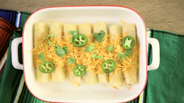 Chicken enchiladas with cheddar cheese and sauce.