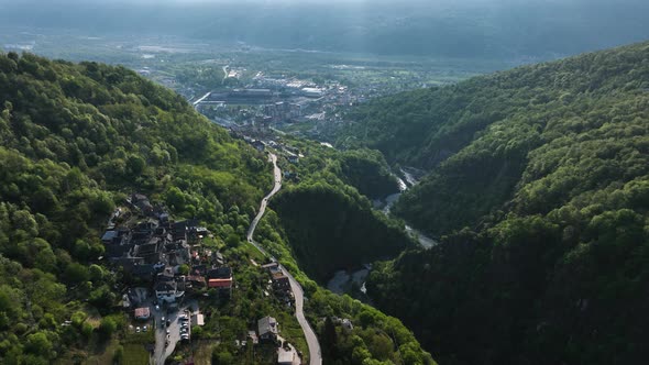 Flight above road through idyllic Italian village in alp valley hillside; drone