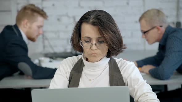 Mature Woman Sitting Behind Table and Using Her Laptop