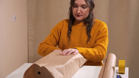 Brunette Woman Wrapping Gift in Kraft Paper