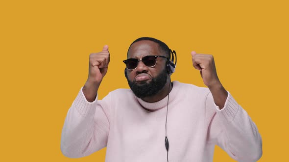 Joyful Bearded Black Man Dancing and Listens Audio Track in Headphones, Feels Very Glad, Wears