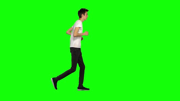 Tall Skinny Teen Guy Is Running on Green Screen Background. Chroma Key,  Shot. Profile View.