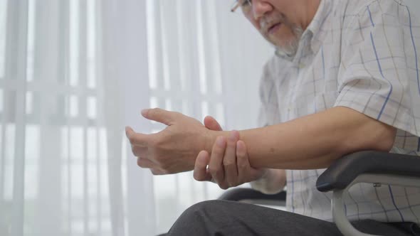 Senior man massaging wrist and arm to relieve suffering from joint pain