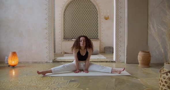 Sporty CurlyHaired Woman Does Yoga Stretching Exercises