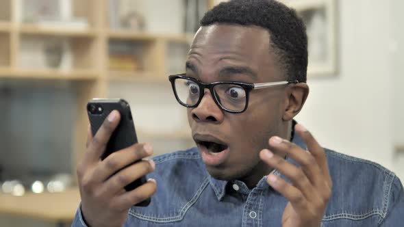 AfroAmerican Man Reacting to Loss on Smartphone