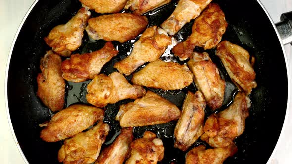 Many Crispy Fried Chicken Wings Pieces in Frying Pan Turning Slowly on Turntable