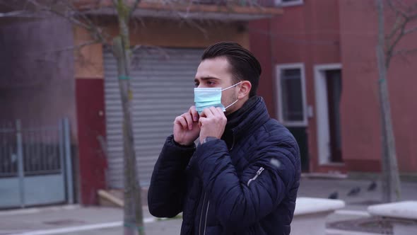 Handsome Brunet Puts on Protective Mask Among Rotating City