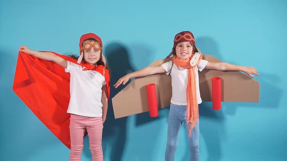 Studio Footage Happy Kids in Toy Airplane Wearing Cloaks Against in Blue Background