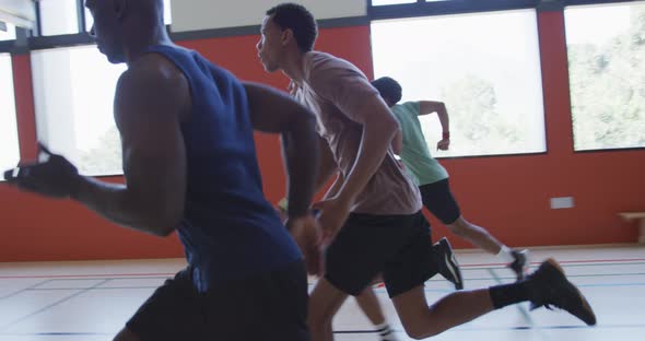 Diverse male basketball team and coach running and wearing sportswear