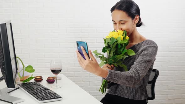 Young Cheerful Mixedrace Woman Making Selfie with Roses Indoor