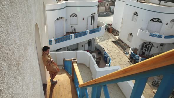 Travel and Beauty Concept. Pretty Woman in Loose Yellow Dress Enjoying Her Holidays on Santorini