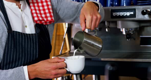 Waiter pouring milk in coffee