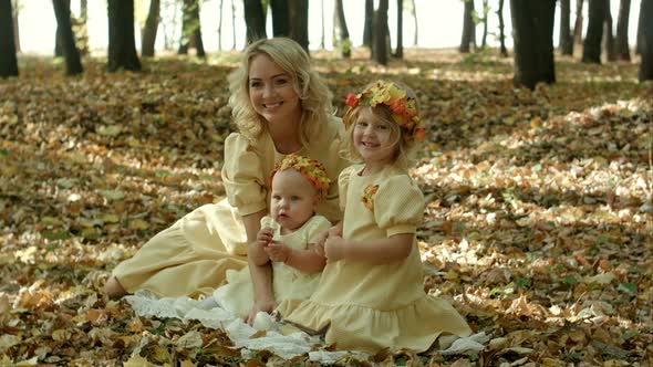 Beautiful Young Woman with Maple Leaves Sitting with Her Baby