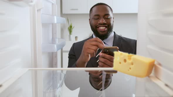 Online ordering of goods from the supermarket. Business man in suit looks into an empty refrigerator