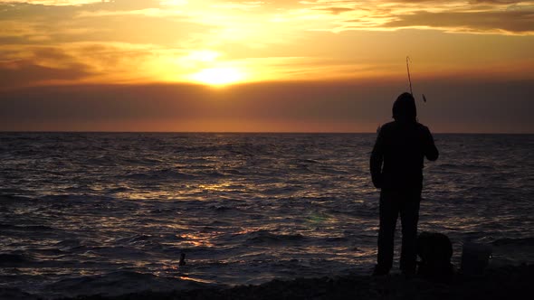 Silhouette of a Man Tightens a Fishing Line Reel of Fish Summer