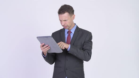 Studio Shot of Stressed Businessman Using Digital Tablet and Getting Bad News