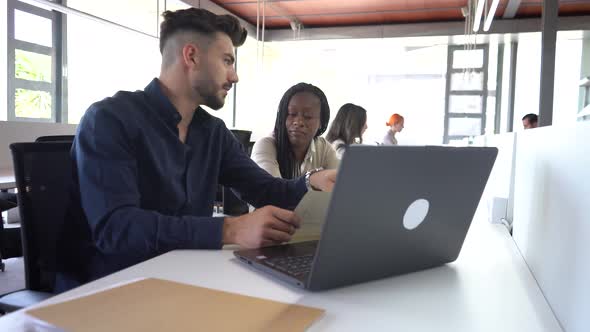 Diverse colleagues working at table in office