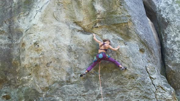 Young Woman Climber Falling Down After Failed Attemp to Climb Steep Wall of Rocky Mountain