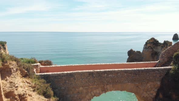 Arch bridge at Paria dos Estudantes, Lagos, Algarve. Pullback fly over.