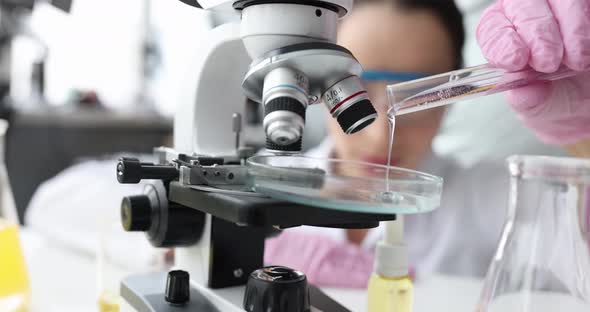 Woman Chemist Pours Liquid Into Test Tube for Examination on Microscope