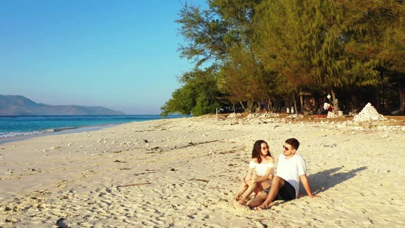 Two people engaged on marine seashore beach journey by blue ocean and white sandy background of Indo