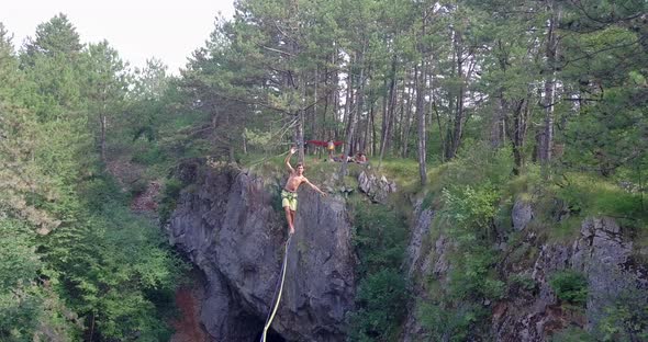 A man falls while slacklining on a tightrope in the mountains