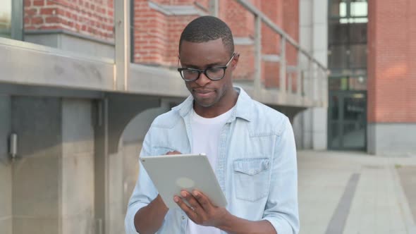 African Man Working on Tablet While Walking in Street